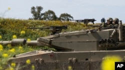 Israeli soldiers move on the top of a tank near the Israeli-Gaza border, as seen from southern Israel, March 21, 2024.