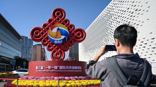 A man takes photos of an installation of the Belt and Road Forum in Beijing on Oct. 16, 2023.