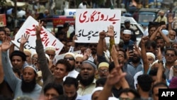A trader holds a placard reading 'prevent unemployment from rising' during a protest at a street in Karachi, Aug. 23, 2023, against the surge in petrol and electricity prices as Pakistan endures soaring inflation.