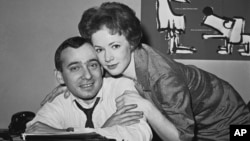 FILE - Actress Piper Laurie hugs her husband-to-be, drama reporter and critic Joseph M. Morgenstern, at his desk at the Herald-Tribune in New York, after their engagement, Dec. 28, 1961.