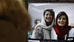 FILE - A woman looks at a computer screen with a photo of Iranian journalists Niloufar Hamedi, left, and Elaheh Mohammadi, right, in Nicosia, Cyprus, Nov. 2, 2022. 