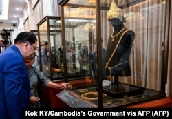 Perdana Menteri Kamboja Hun Sen (kiri) melihat perhiasan Angkor yang dicuri yang saat ini sedang dipamerkan di Phnom Penh. (Foto: via AFP)
