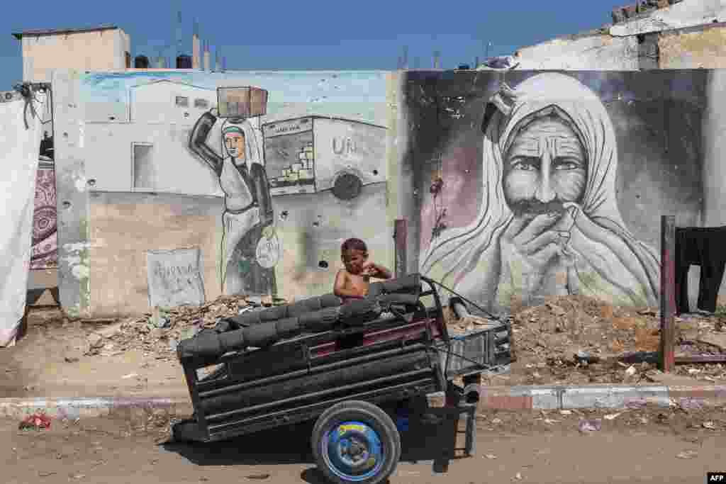 A boy reacts as he sits in the back of a trailer at a makeshift displacement camp set up on a roadside in Deir el-Balah in the central Gaza Strip, amid the ongoing conflict between Israel and the Palestinian Hamas movement.