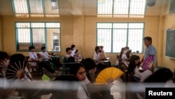 Grade 12 students use hand fans as they attend a class at the Commonwealth High School in Quezon City, Metro Manila, Philippines, April 18, 2024. 