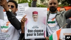 FILE - Demonstrators gather in front of the Embassy of Niger in Paris, in support of Nigerien President Mohamed Bazoum and ECOWAS, Aug. 5, 2023.