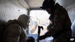 A Ukrainian police officer helps an elderly woman evacuate to a safe area in Chasiv Yar near Bakhmut, Ukraine, March 4, 2023.