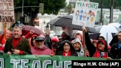 ARCHIVO - Miles de maestros y simpatizantes sostienen carteles bajo la lluvia durante una manifestación, el 14 de enero de 2019 en Los Ángeles.