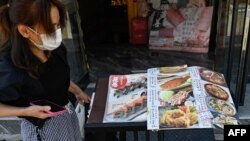在北京，日本驻华大使馆附近的一家日本餐馆前一名女子在看餐馆菜单。（2023年8月29日）