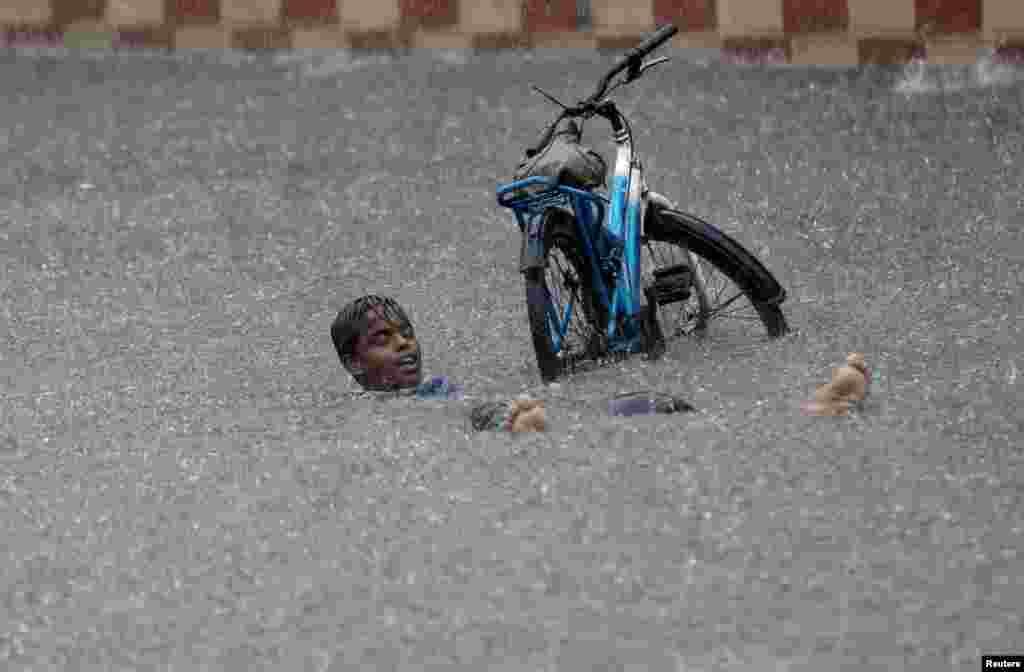 A boy plays on a flooded road amid heavy rainfall in Ahmedabad, India.