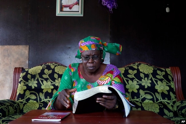 Arowolo Mofeoluwa Victoria, a retired Civil Servant, who said she has lost two houses due to coastal erosion, reads a bible inside her house in Ayetoro, Southwest Nigeria, Friday, April 5, 2024. (AP Photo/Dan Ikpoyi)