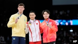 From left, silver medalist Illia Kovtun, of Ukraine, poses with gold medalist Zou Jingyuan, of China, and bronze medalist Shinnosuke Oka, right, of Japan, after the men's individual parallel bars finals at the Olympics, in Paris, France, Aug. 5, 2024. 