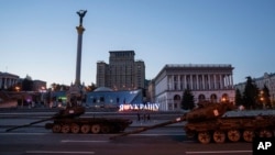 People walk in front of destroyed Russian tanks installed on Khreschatyk street during Independence Day in downtown of Kyiv, Ukraine, Aug. 24, 2023.