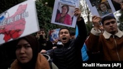 (FILE) Protesters chant slogans as they hold posters and pictures of victims during a protest against China's brutal crackdown on ethnic group Uyghurs.