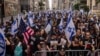 People hold Israeli flags, with one carrying a U.S. flag, as they gather ahead of the annual Israel Day Parade on Fifth Avenue in New York City, June 2, 2024.