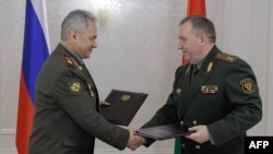Russian Defense Minister Sergei Shoigu and his Belarusian counterpart Viktor Khrenin shake hands after signing an agreement on the relocation of some of Russia's tactical nuclear weapons to Belarus, in Minsk, May 25, 2023. (Russian Defense Ministry via AFP)