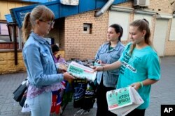 Volunteers of the New People political party distribute their party newspapers in a street prior to local elections in Donetsk, the capital of Russian-controlled Donetsk region, eastern Ukraine, Sept. 7, 2023.