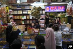 Orang-orang berbelanja kue dan makanan ringan menjelang perayaan hari raya Idulfitri di sebuah pasar di Jakarta, Rabu, 12 April 2023. (AP/Tatan Syuflana)