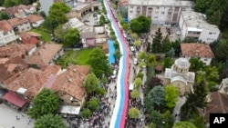 People hold a giant banner in the colors of the Serbian flag during a protest in the town of Zvecan, northern Kosovo, May 31, 2023. 