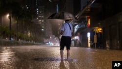 A pedestrian waits for a bus on a flooded street following heavy rainstorms in Hong Kong, Sept. 8, 2023. 