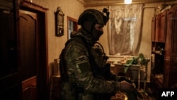 A serviceman, call sign 'Virus,' prepares to patrol the front line from an abandoned house near Bakhmut, Ukraine, on Feb. 18, 2023.