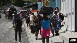 Una residente abandona la comuna de Carrefour Feuilles en Puerto Príncipe el 15 de agosto de 2023, mientras la violencia de pandillas continúa golpeando la capital de Haití