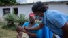 Msaidizi wa masuala ya Afya Ester Lunga (kulia) akitoa dozi ya chanjo ya polio kwa mtoto katika kitongoji cha Chilinde kilichopo katika mji wa Lilongwe Malawi, Machi 21, 2022. Picha na Amos Gumulira / AFP.
