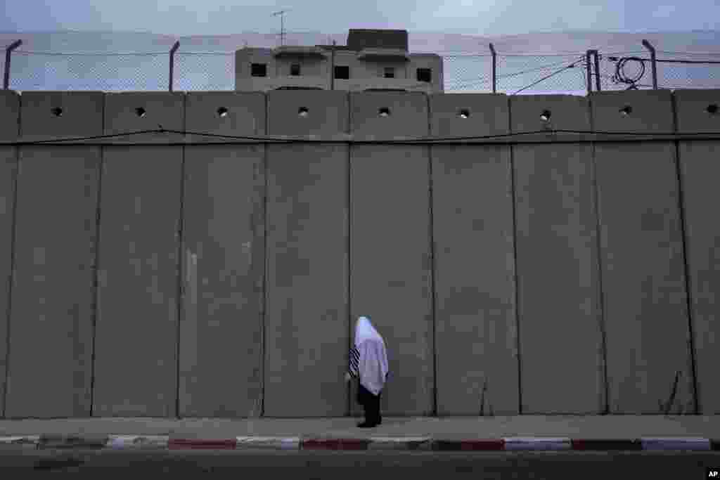 An ultra-Orthodox Jewish man prays at the concrete separation barrier built by Israel to secure Rachel&#39;s Tomb, Judaism&#39;s third holiest shrine, in the West Bank town of Bethlehem during the Jewish holiday of Sukkot.