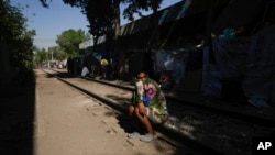 A migrant from Maracaibo, Venezuela, sits on a railroad track lined by makeshift tents where migrants take refuge in Mexico City, March 26, 2024. 