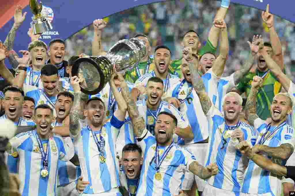 Argentina&#39;s Lionel Messi holds the trophy as celebrating with teammates after defeating Colombia in the Copa America final soccer match in Miami Gardens, Florida.