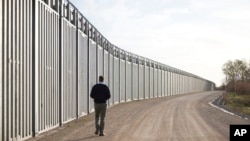 FILE - Greece's Prime Minister Kyriakos Mitsotakis walks next to a border wall near the town of Feres, along the Evros River which forms the frontier between Greece and Turkey, March 31, 2023. (Greek Prime Minister's Office via AP)