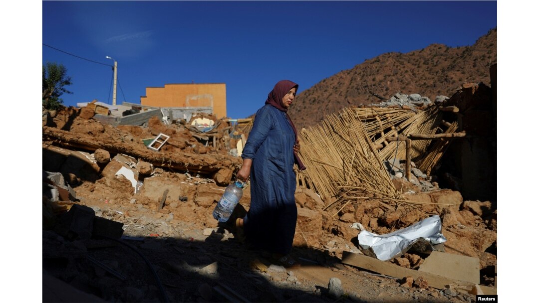 A woman carries a bottle, as she walks near rubble, in the aftermath of a deadly earthquake, in a hamlet on the outskirts of Talat N'Yaaqoub, Morocco, Sept. 11, 2023.