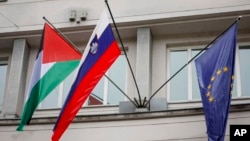 A Palestinian flag flies next to a Slovenian, center, and a European Union flag, right, at the government building in Ljubljana, Slovenia, May 30, 2024.