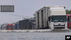 In this photo released by Xinhua News Agency, vehicles drive through a flood waters in Shenyang, northeastern China's Liaoning Province, July 26, 2024. 