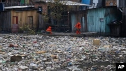 FILE - City workers remove garbage floating on the Negro River, which has a rising water level due to rain, in Manaus, Amazonas state, Brazil, June 6, 2022.