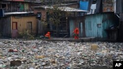 FILE - City workers remove garbage floating on the Negro River, which has a rising water level due to rain, in Manaus, Amazonas state, Brazil, June 6, 2022.