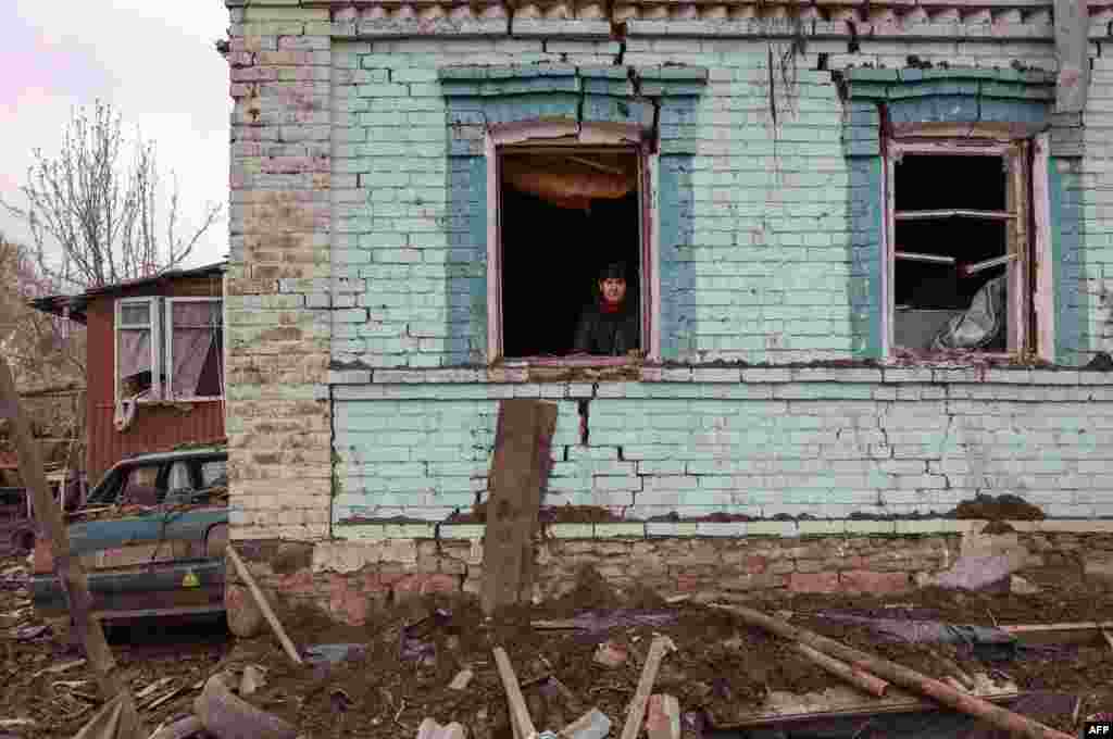 A local resident looks out from her partially destroyed house after missile strikes, in the town of Kostyantynivka, Donetsk region, amid Russia's military invasion on Ukraine.