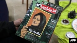 FILE - A person holds a copy of Iranian magazine Andisheh reporting on the death of Mahsa Amini, who died after being arrested by the Islamic republic's "morality police," in Tehran, Iran, March 14, 2023.