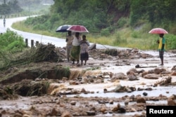 Locals in the Chiradzulu district of Malawi look at the damage on a road after mudslides and rockfalls in the area caused by the aftermath of Cyclone Freddy in Blantyre, Malawi, March 15, 2023.