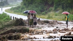 Locals in the Chiradzulu district of Malawi look at the damage on a road after mudslides and rockfalls in the area caused by the aftermath of Cyclone Freddy in Blantyre, Malawi, March 15, 2023.