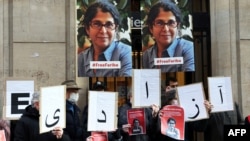Kolega dari akademisi Fariba Adelkhah membawa poster yang berisi dukungan terhadap Adelkhah dalam aksi Paris, Prancis, pada 13 Januari 2022. Adelkhah termasuk dalam sejumlah figur terkemuka Iran yang ditahan oleh pemerintah negara tersebut. (Foto: AFP/Thomas Coex)