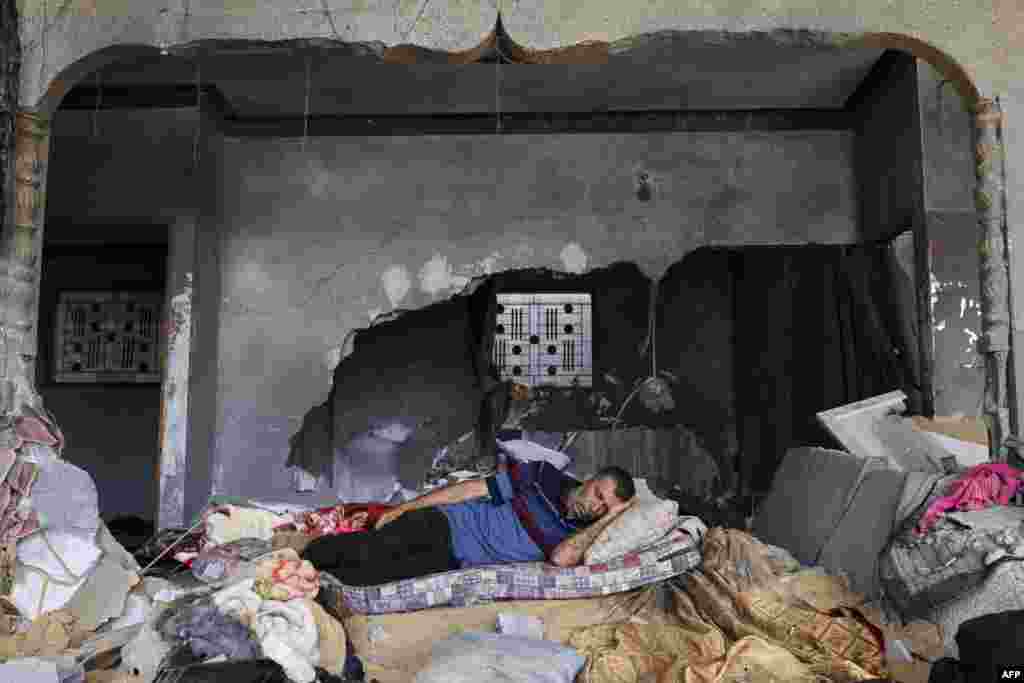 A Palestinian man sleeps in his house, which was heavily damaged during fighting between Israel and Islamic Jihad militants in the beginning of May 2023, in Beit Lahia in the northen Gaza Strip.