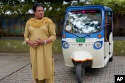 Preethi, perempuan transgender berusia 38 tahun, berdiri di samping becak listriknya saat diwawancarai The Associated Press di Bengaluru, India, Senin, 10 Juli 2023. (AP/Aijaz Rahi)