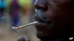 FILE - A young man smokes kush, a derivative of cannabis mixed with synthetic drugs like fentanyl and tramadol and chemicals like formaldehyde, in Freetown, Sierra Leone, April 29, 2024. 