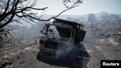 A damaged vehicle is seen in an area burned during a wildfire, in Kitsi, near the town of Koropi, Greece, June 19, 2024.