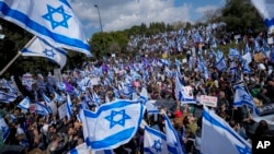 Israelis wave national flags during protest against plans by Prime Minister Benjamin Netanyahu's new government to overhaul the judicial system, outside the Knesset, Israel's parliament, in Jerusalem, Monday, Feb. 13, 2023. (AP Photo/Ohad Zwigenberg)