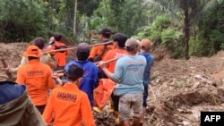 This handout photo released on April 14, 2024 by the National Search and Rescue Agency (BASARNAS) shows rescuers carrying a body bag at a landslide site in Tana Toraja, South Sulawesi. 