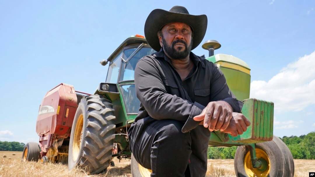 FILE - Farmer John Boyd Jr., poses for a portrait during a break from baling hay at his farm in Boydton, Va., May 27, 2021. 