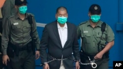 FILE - Jimmy Lai is escorted by Correctional Services officers to get on a prison van before appearing in a court in Hong Kong, Dec. 12, 2020.