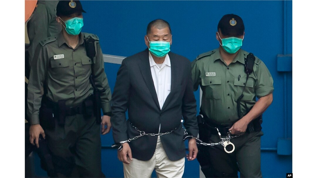 FILE - Jimmy Lai is escorted by Correctional Services officers to get on a prison van before appearing in a court in Hong Kong, Dec. 12, 2020.
