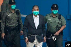 FILE - Jimmy Lai is escorted by Correctional Services officers to get on a prison van before appearing in a court in Hong Kong, Dec. 12, 2020.